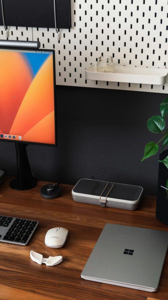 a desk with a laptop, keyboard, mouse and a monitor